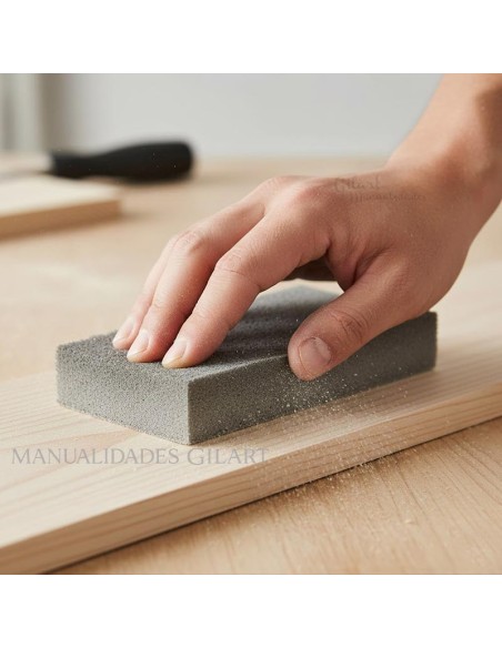 Primer plano de mano lijando una tabla de madera lisa con taco de esponja abrasiva.