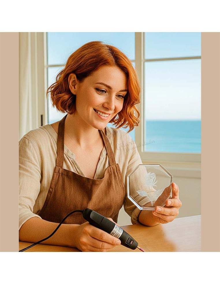 Creación artesanal de grabado sobre cristal con diseño floral utilizando herramienta rotativa.