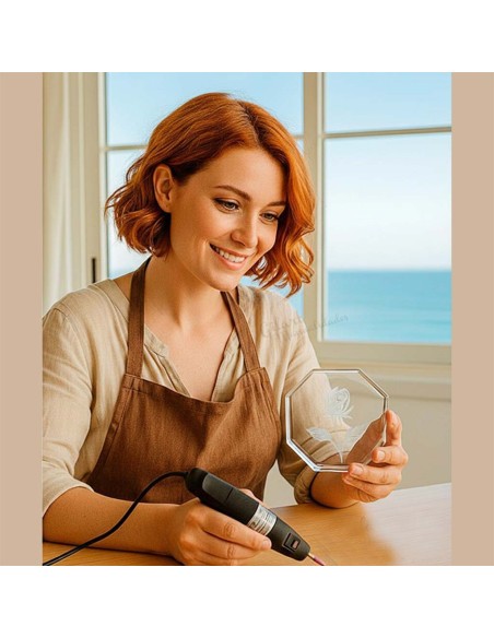 Creación artesanal de grabado sobre cristal con diseño floral utilizando herramienta rotativa.